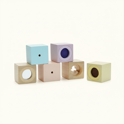 PlanToys Sensory Blocks, six wooden cubes with windows, mirrors and textures, on a plain cream background
